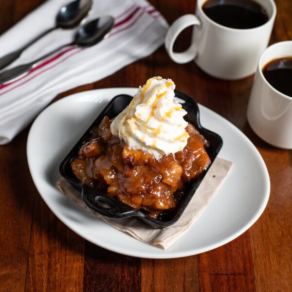 Image of a scrumptious desert. The Salted Caramel Apple Strudel with whipped cream and a caramel drizzle on top.
