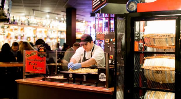 A chef is standing behind a pasta engine, sorting through some freshly cut sourdough pasta.