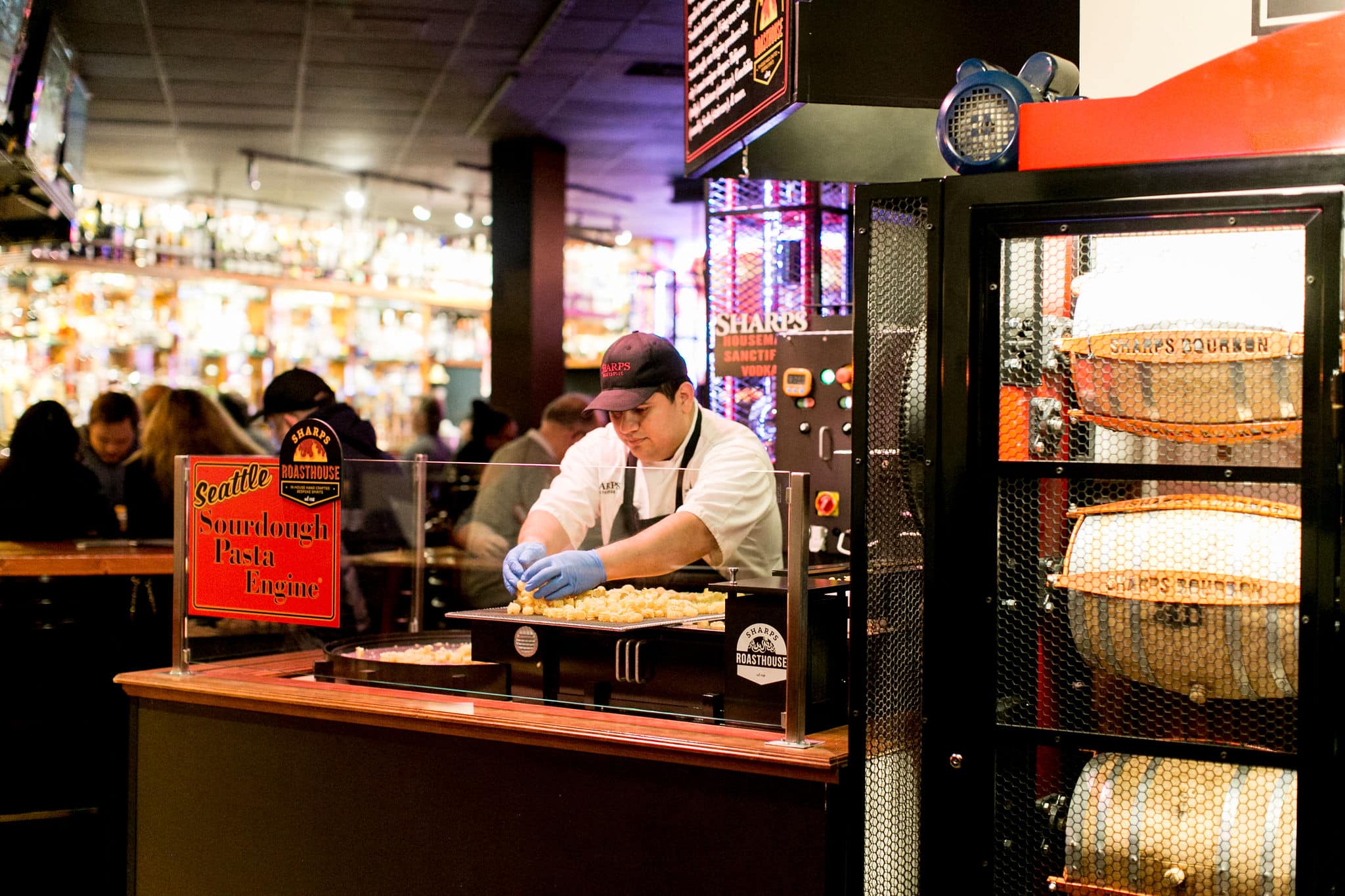 A chef is standing behind a pasta engine, sorting through some freshly cut sourdough pasta. 