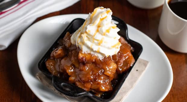 Image of a scrumptious desert. The Salted Caramel Apple Strudel with whipped cream and a caramel drizzle on top.